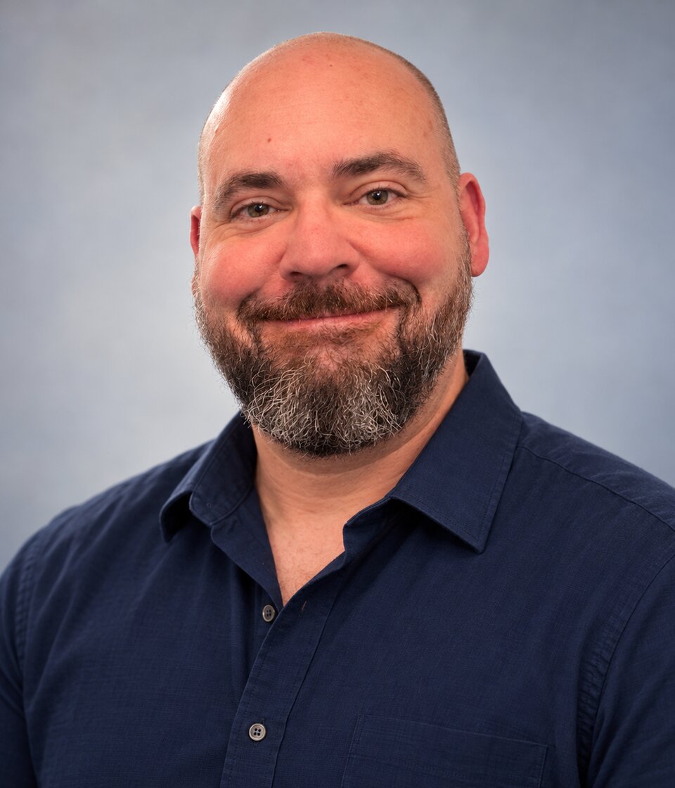 Kyle Welch, smiling, in a navy blue shirt.
